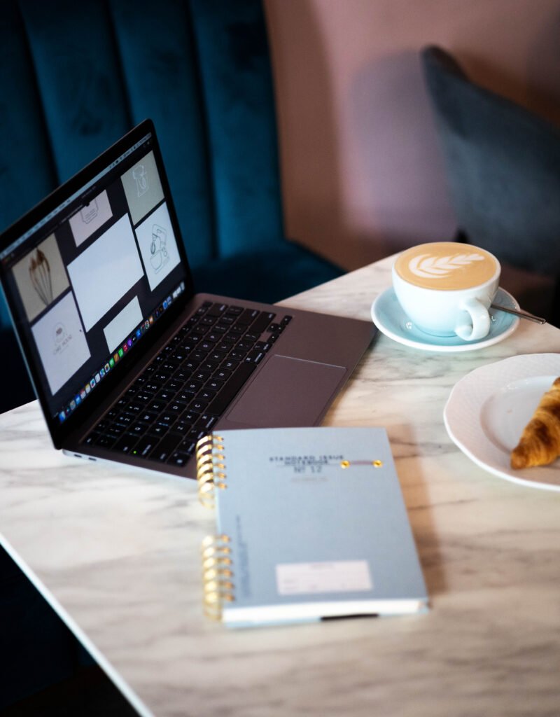 A sleek modern office setup featuring dual monitors, Apple devices,coffee and creative decor in an indoor workspace.